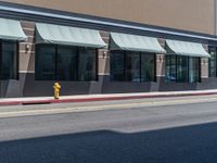 yellow fire hydrant and sidewalk next to storefront on street side of city street