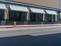 yellow fire hydrant and sidewalk next to storefront on street side of city street