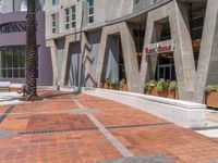 a skateboarder in orange shirt on street corner next to building with plants outside