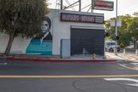 a building painted like obama with a business sign on it's side and a fire hydrant near the street