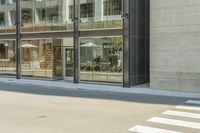 the woman walks down the sidewalk in her black coat outside the office buildings along with large windows