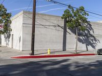 an intersection with a street corner and building in front of it, surrounded by trees and wires