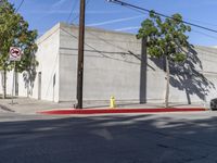 an intersection with a street corner and building in front of it, surrounded by trees and wires