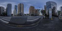 an empty street in a very large city with tall buildings in the background, taken from the ground