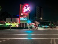 the building next to the street is lit up with neon lights and signs that read dairy