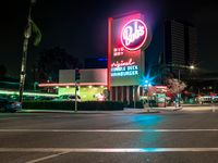 the building next to the street is lit up with neon lights and signs that read dairy