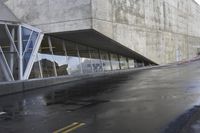 a white sign sitting on the side of a building next to a sidewalk with water on it