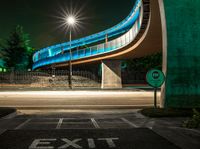 an empty road at night with a blue bridge in the background and text exit only on it