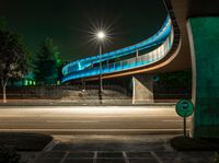 an empty road at night with a blue bridge in the background and text exit only on it