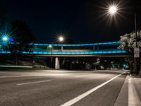 a street at night with a blue bridge and car lights on it's sides