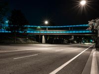 a street at night with a blue bridge and car lights on it's sides