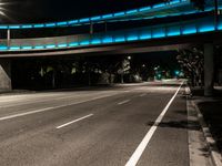 a street at night with a blue bridge and car lights on it's sides