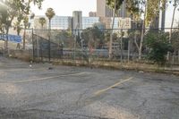 a parking lot with graffiti and trees in the back ground next to the fence and a man walking next to the vehicle