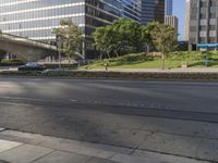 a long empty street in the middle of the city with buildings and a bridge above it