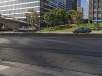 a long empty street in the middle of the city with buildings and a bridge above it