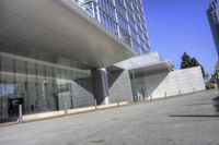 a big building with a glass facade next to a street and sidewalk in front of it