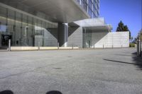 a big building with a glass facade next to a street and sidewalk in front of it