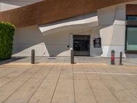 an entrance to a large building with parking meters in the foreground and a door with a ticket booth at it