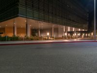 an office building on a dark night with bright lights shining down from the window and below