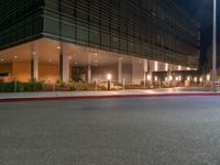 an office building on a dark night with bright lights shining down from the window and below