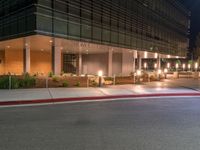 an office building on a dark night with bright lights shining down from the window and below