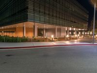 an office building on a dark night with bright lights shining down from the window and below