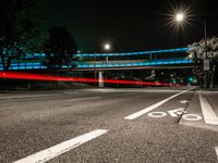 the view of a street from under some lights at night, with two bicycle lanes on the sidewalk