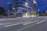 a cross walk with a building in the background on a cloudy day at night time