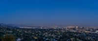 a cityscape view at dusk with a full moon behind it and houses, in the foreground