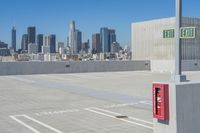 there is a fire box in the parking lot with city in the background, from which it would be a public space to park on top