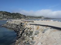 view of some sand and rocks on a river and a bridge in the foreground