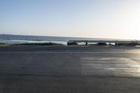 an empty road near a beach and waves as well as cars on the sand and houses on the beach