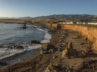 a grassy field by the shore and a cliff with rocks in the ocean in the background