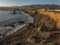 a grassy field by the shore and a cliff with rocks in the ocean in the background