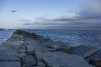 a sea wall lined with rocks sitting next to the ocean in front of the water