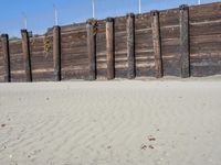 a fence that is next to some sand and a dirt field with two people on it