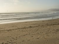 a beach is seen with people walking on it and the ocean is behind them and one person on the sand