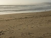 a beach is seen with people walking on it and the ocean is behind them and one person on the sand