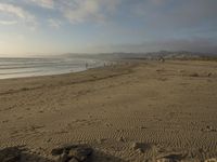 a beach is seen with people walking on it and the ocean is behind them and one person on the sand