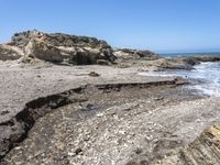 a beach has large rocks along with a very nice coastline area to the front and to the back