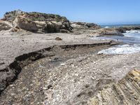 a beach has large rocks along with a very nice coastline area to the front and to the back