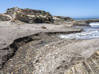 a beach has large rocks along with a very nice coastline area to the front and to the back