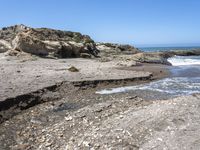 a beach has large rocks along with a very nice coastline area to the front and to the back