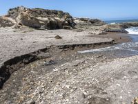 a beach has large rocks along with a very nice coastline area to the front and to the back