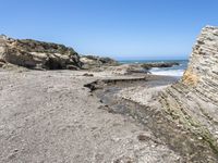 a beach has large rocks along with a very nice coastline area to the front and to the back