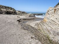 a beach has large rocks along with a very nice coastline area to the front and to the back