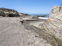 a beach has large rocks along with a very nice coastline area to the front and to the back