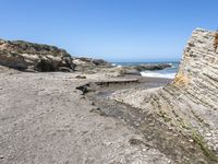 a beach has large rocks along with a very nice coastline area to the front and to the back