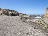 a beach has large rocks along with a very nice coastline area to the front and to the back