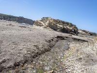 a beach has large rocks along with a very nice coastline area to the front and to the back